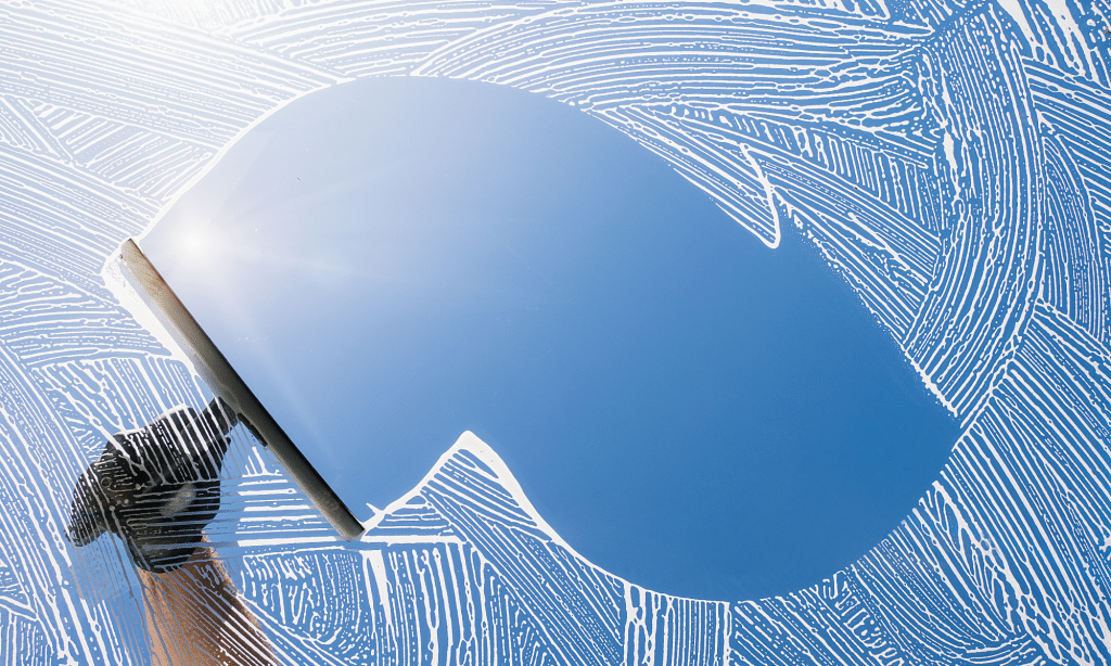 Window being cleaned with a squeegee, leaving a clear, streak-free surface